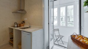 Une cuisine compacte dotée d’un évier encastré, d’un petit réfrigérateur et d’une fenêtre donnant sur un paysage urbain.