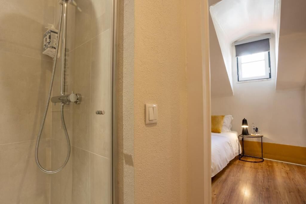 Ein Hotelzimmer mit Dusche, einem Bett, einem Nachttisch mit Lampe und einem Fenster.