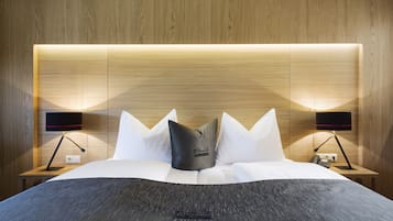 Una habitación de hotel moderna con cabecera de madera, ropa de cama blanca y dos lámparas de noche.