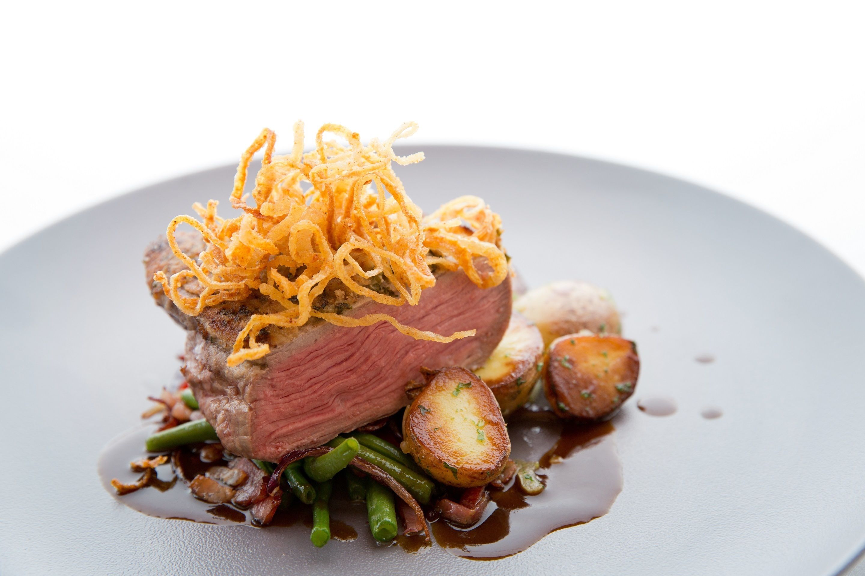 A plated dish with a piece of meat, vegetables, and a sauce.