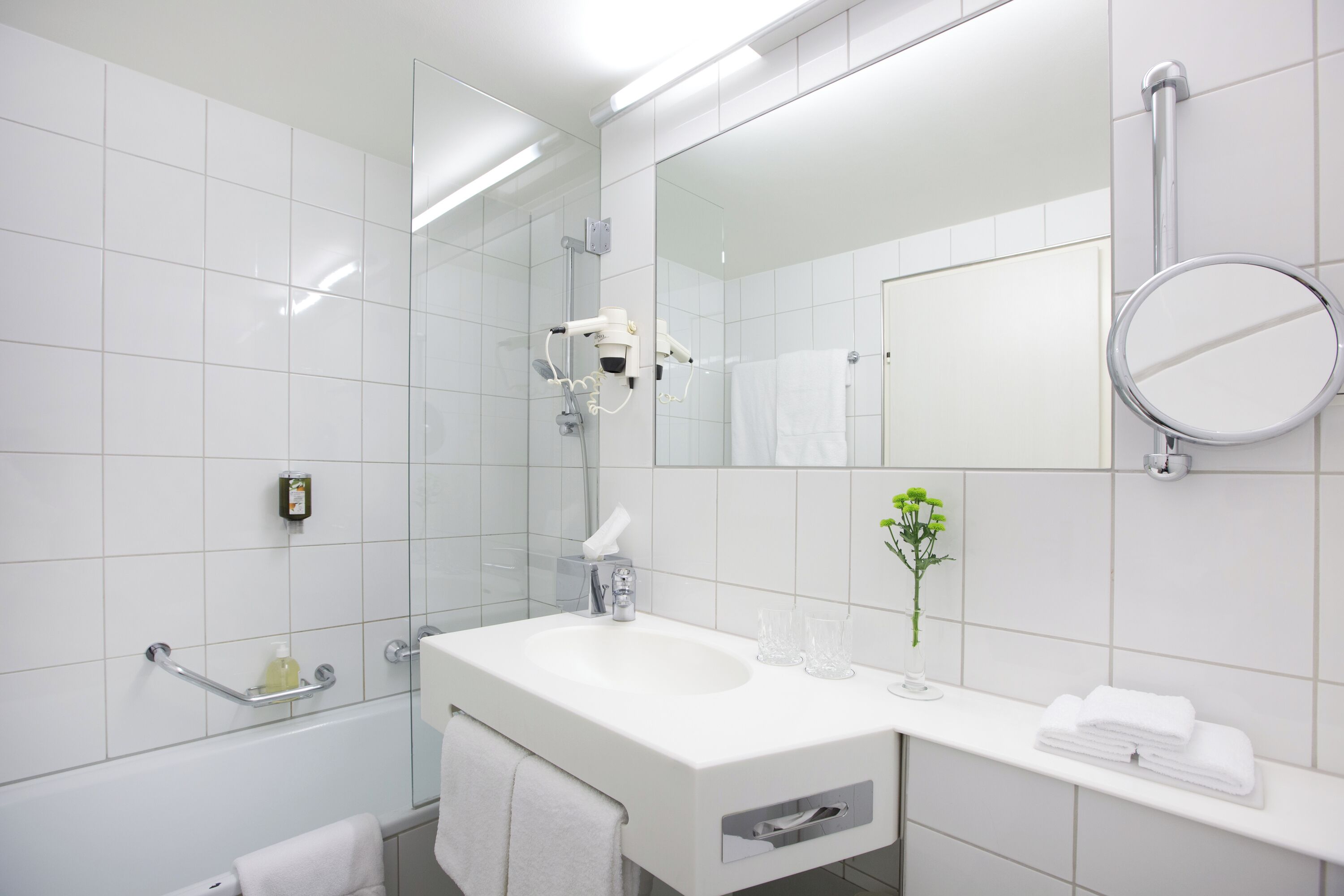 Ein modernes Badezimmer mit Waschbecken, Spiegel und Duschkabine aus Glas.
