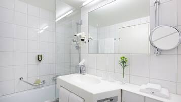 Ein modernes Badezimmer mit Waschbecken, Spiegel und Duschkabine aus Glas.