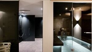 Un bany modern amb un cubicle de dutxa de vidre, un sòl de marbre i un sostre de fusta.