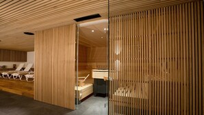 Zona d'spa moderna amb lamel·les de fusta, sauna i gandules.