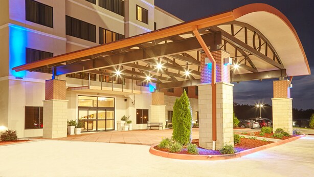 Un hotel de varios pisos con un acceso cubierto, asientos exteriores y zonas ajardinadas.