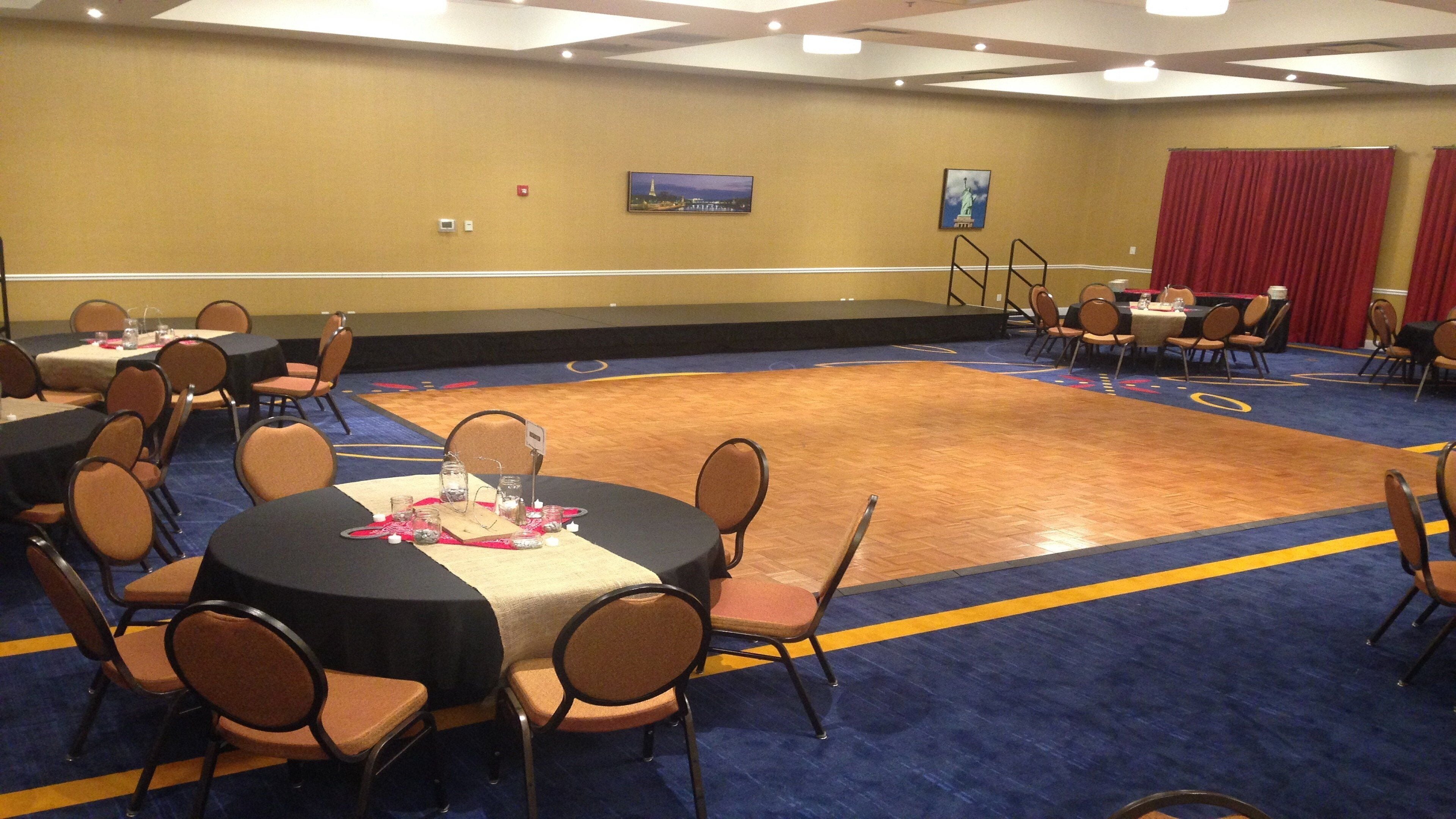 A conference room with round tables, chairs, and a stage area.