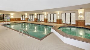 Una amplia piscina cubierta con múltiples carriles, rodeada de sillones de descanso y mesas.