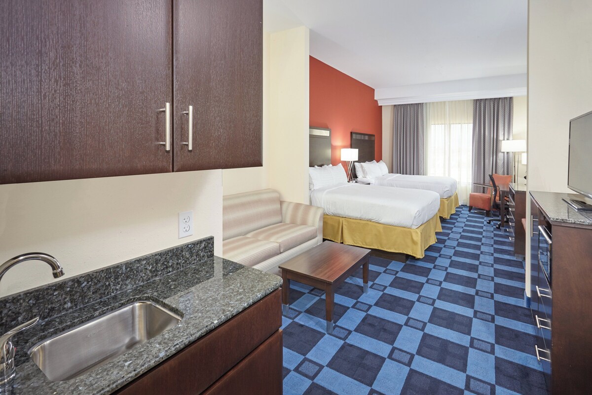 Une chambre d’hôtel avec un lit double, un canapé, une petite table, un lavabo et un téléviseur.