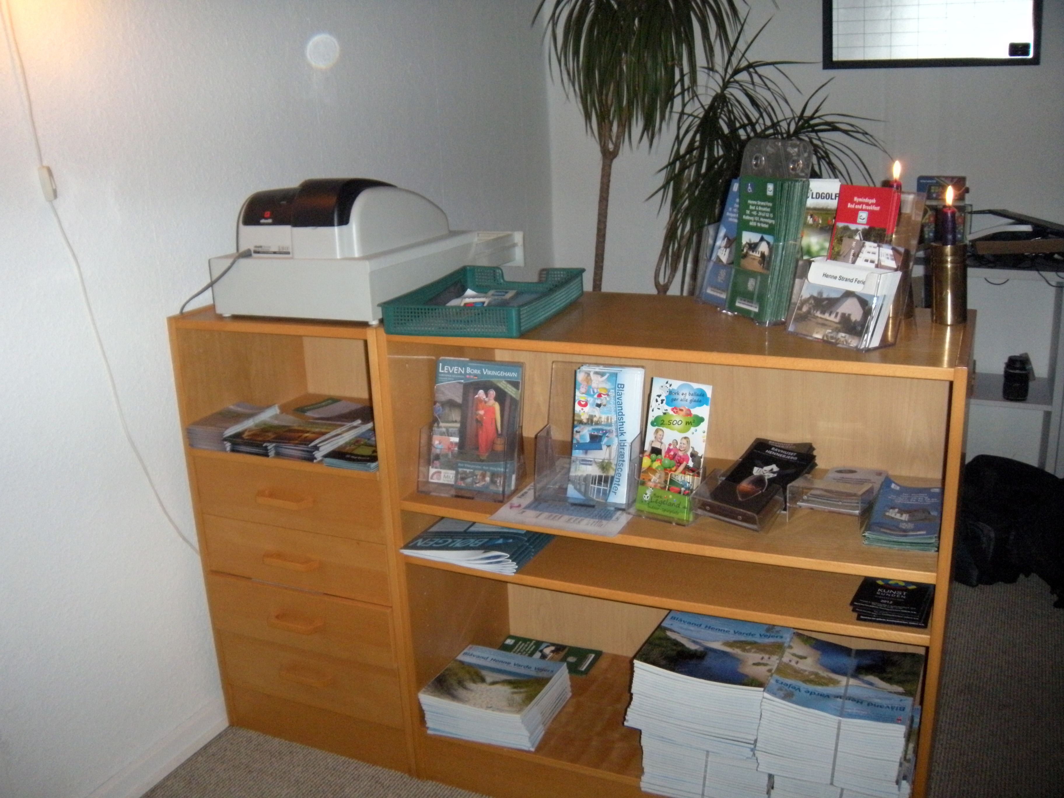 Una habitación con un escritorio de madera, una impresora y varios libros y revistas.
