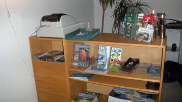 Una habitación con un escritorio de madera, una impresora y varios libros y revistas.
