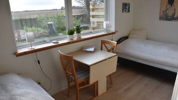Une chambre avec un bureau, un lit et une fenêtre donnant sur un jardin.