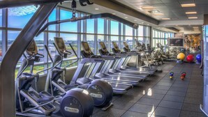Ein Fitnessstudio mit Laufbändern, Übungsbällen und einem großen Fenster mit Blick auf die Stadt.