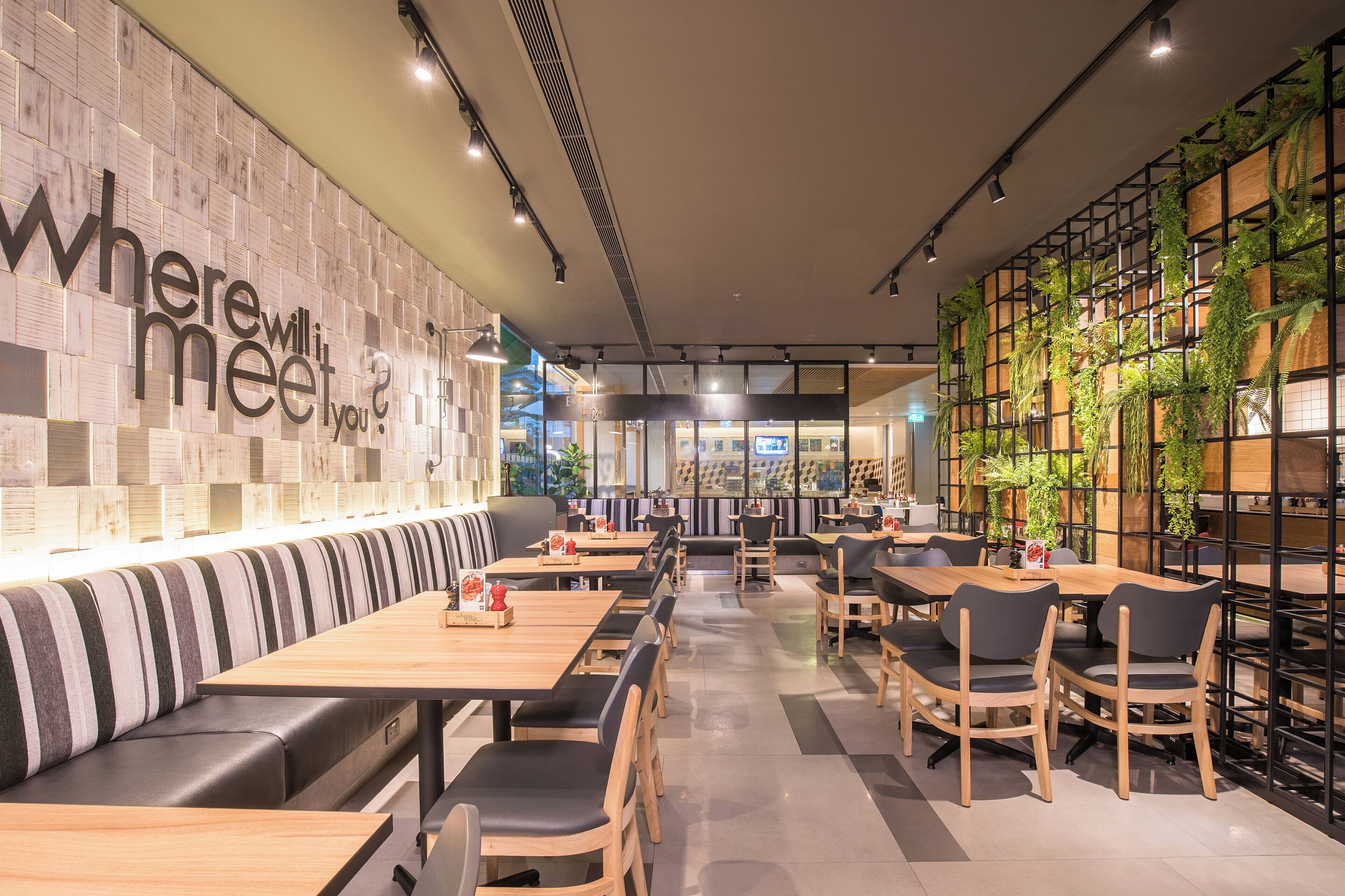 Een modern restaurantinterieur met een lange toonbank, zitjes en tafels.