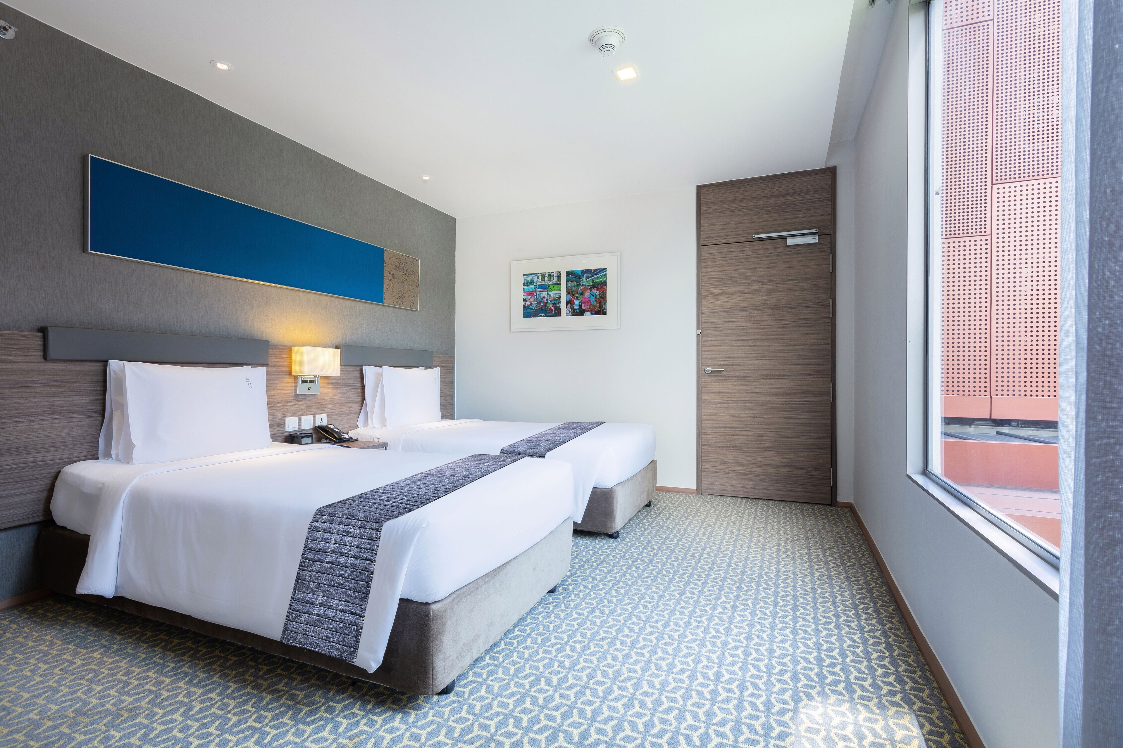 A hotel room with two beds, a large window, and a door.