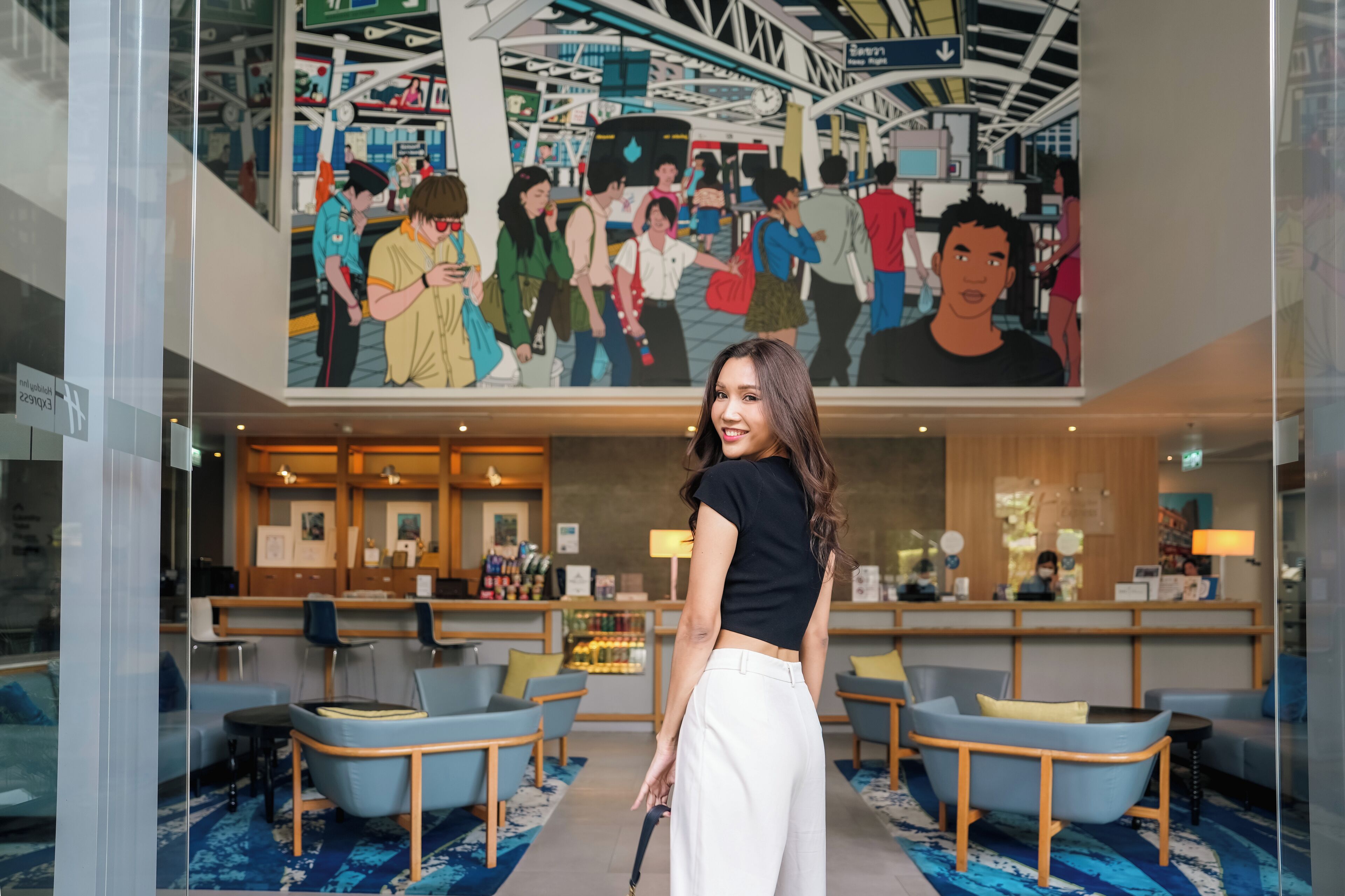A lobby with seating areas, a reception desk, and a large mural depicting people.
