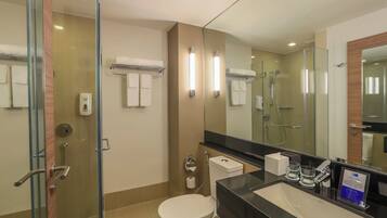 Ein modernes Badezimmer mit Duschkabine aus Glas, Toilette, Waschbecken mit Spiegel und Handtuchhalter.