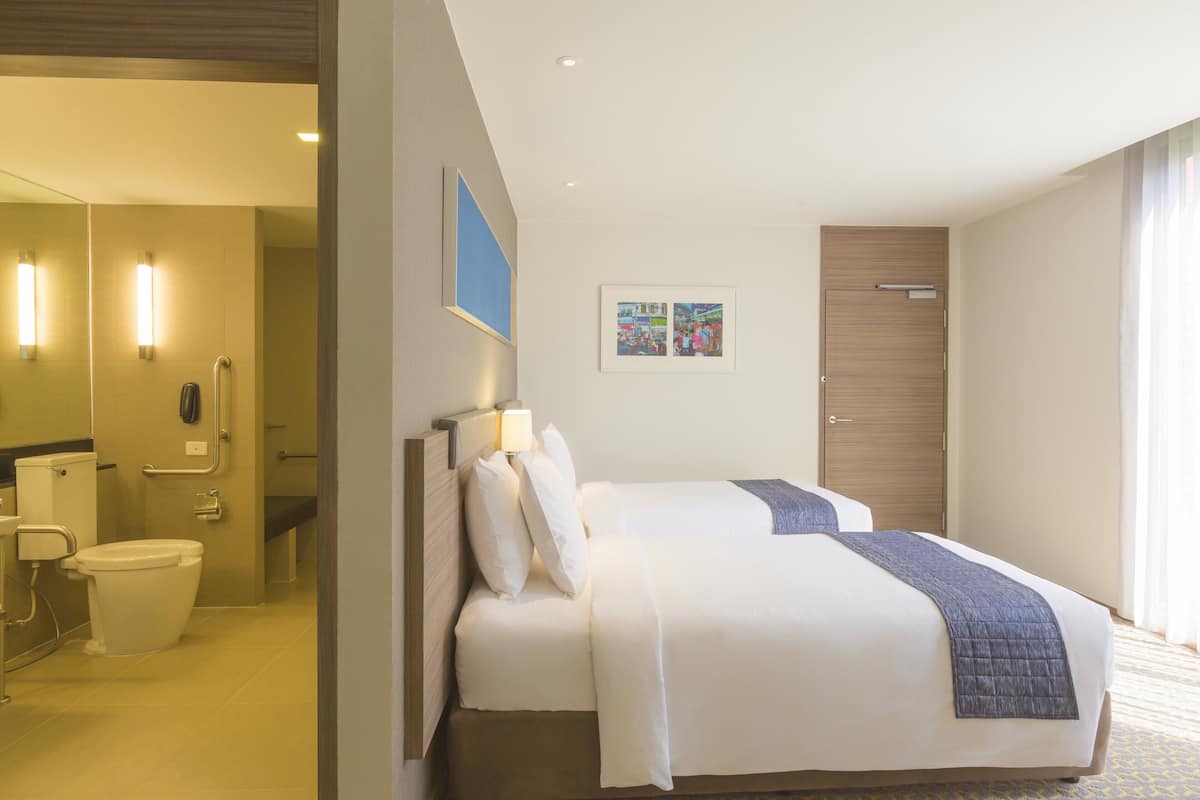 A hotel room with a bed, a bathroom, and a door.