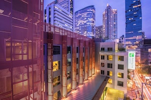 A modern hotel with a glass facade, multiple floors, and a rooftop terrace.