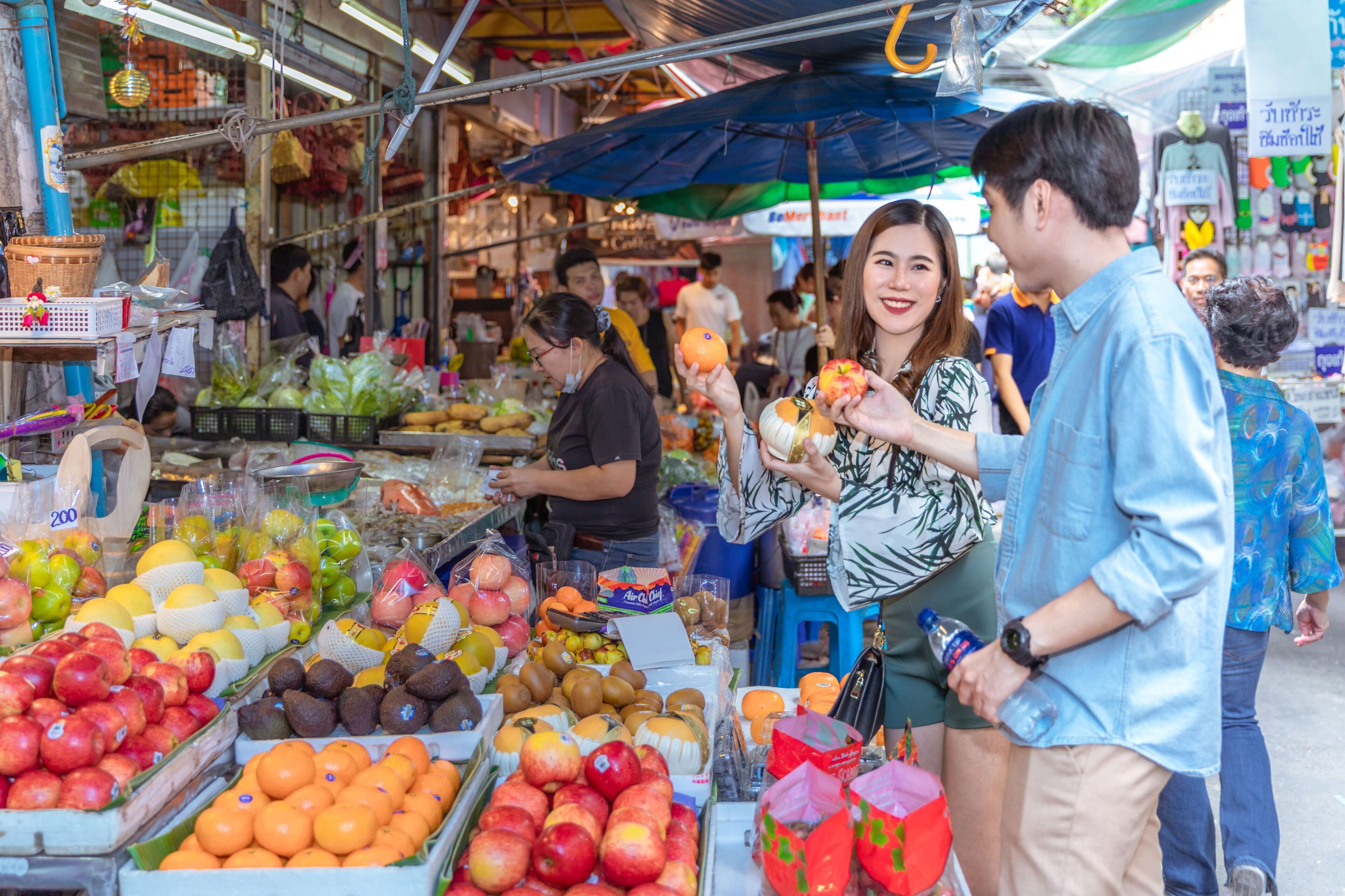 A bustling market with various fruits and vegetables on display.