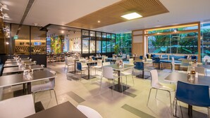 A modern restaurant with multiple tables and chairs, large windows with a view of greenery, and a contemporary interior design. - Holiday Inn Express Bangkok Sathorn by IHG (Bangkok)