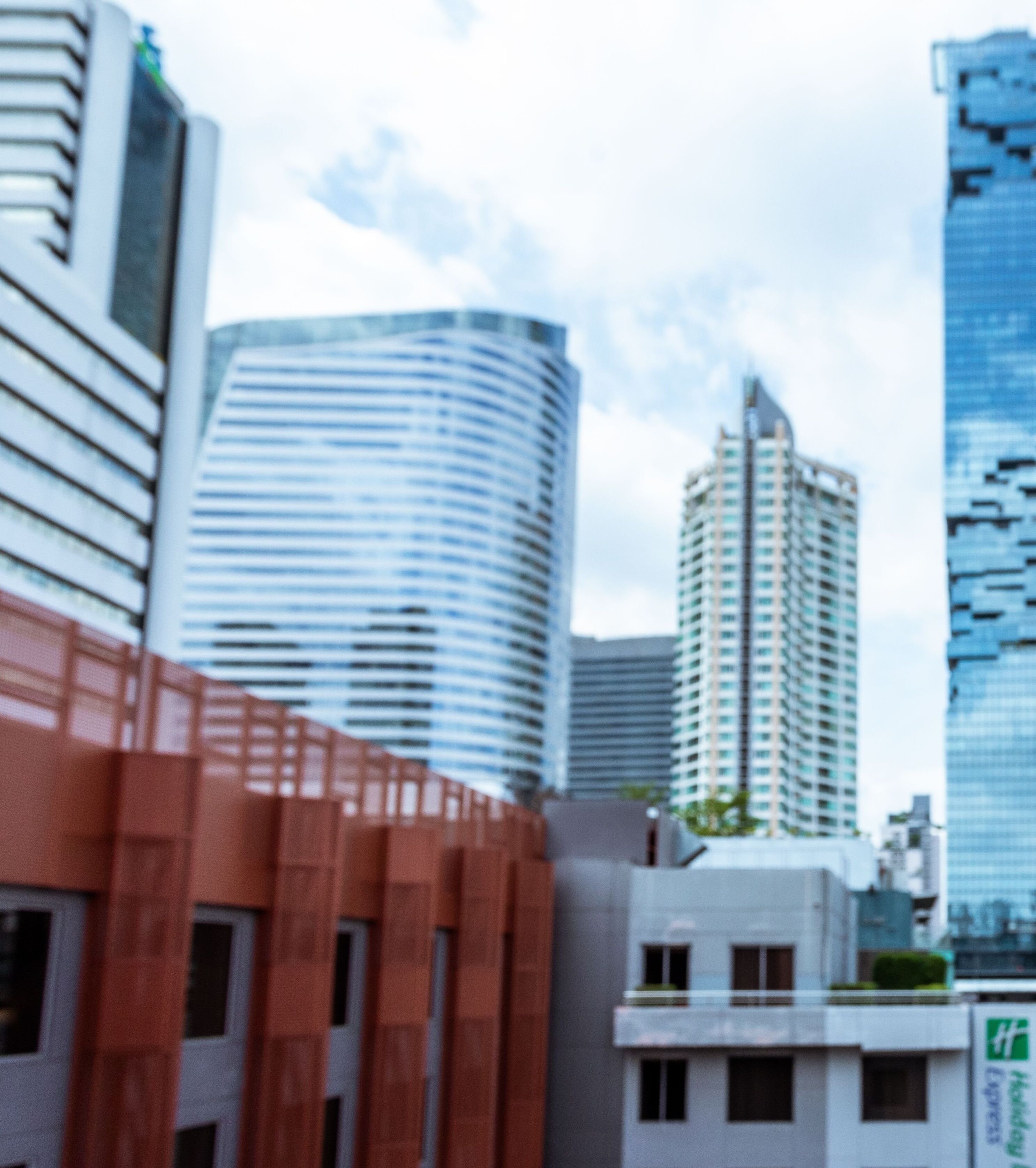 Horizonte urbano moderno com edifícios altos, incluindo uma estrutura curva e um edifício retangular imponente.