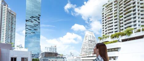 Ein Hochhaus mit moderner Glasfassade, umgeben von weiteren hohen Gebäuden und wolkenlosem, blauem Himmel.