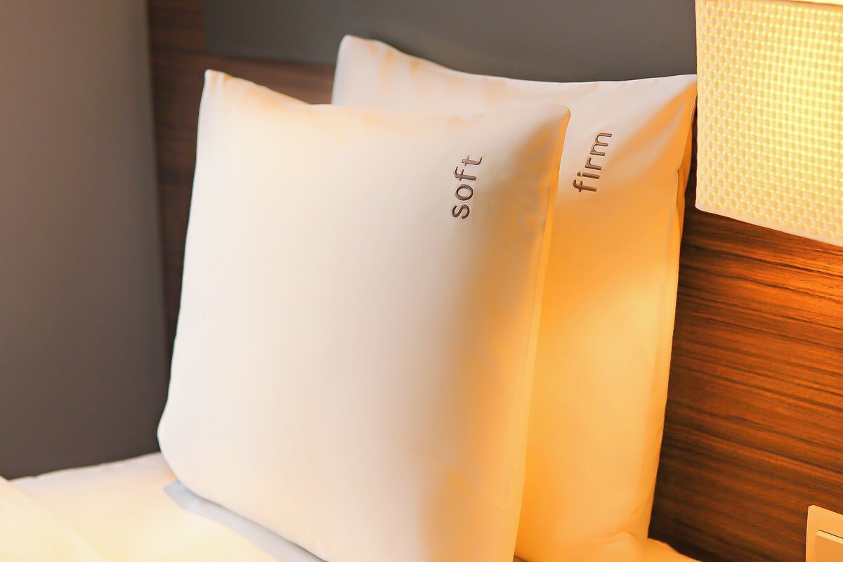 Two pillows with the words "soft" and "firm" on them, placed on a bed with a wooden headboard.