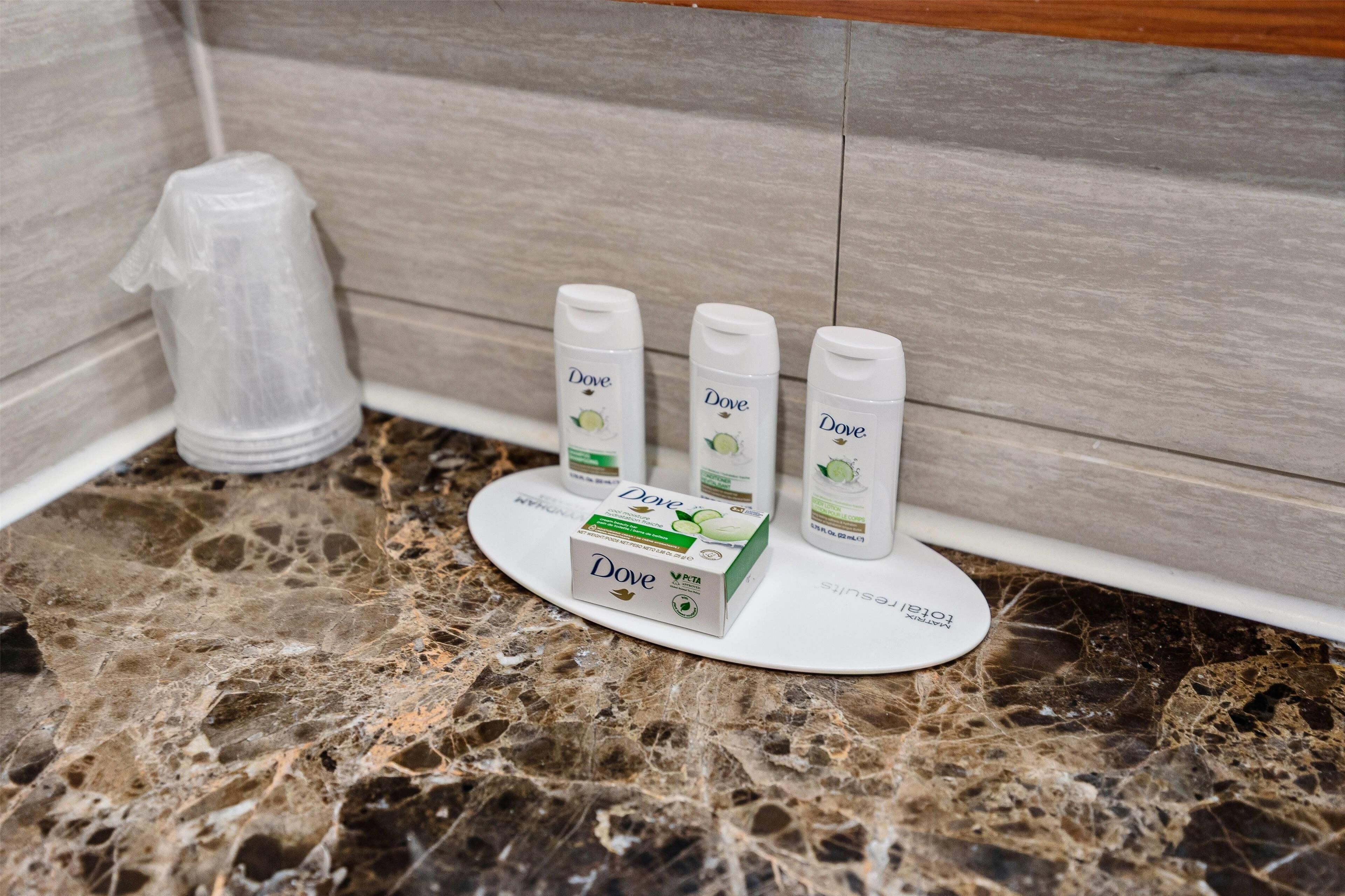 A bathroom counter with Dove personal care products, including a bottle, two tubes, and a box.