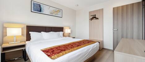 Habitación de hotel moderna con una cama grande, lámparas de noche, un armario de madera y una obra de arte enmarcada en la pared.