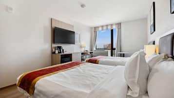 Ett hotellrum med två sängar, en TV, ett skrivbord med en kaffebryggare och utsikt över staden.