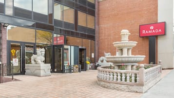 Un patio con una fuente, una estatua y un cartel del hotel Ramada.