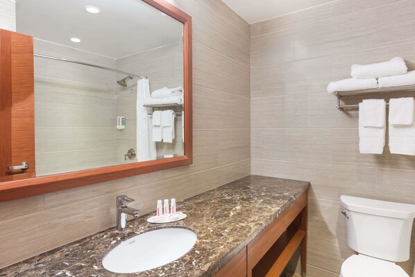 A bathroom with a marble sink, a large mirror, a shower, and a towel rack.