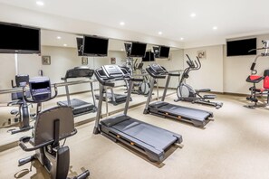 A gym with treadmills, exercise bikes, and a stationary bike. - Ramada by Wyndham Flushing Queens (Flushing)