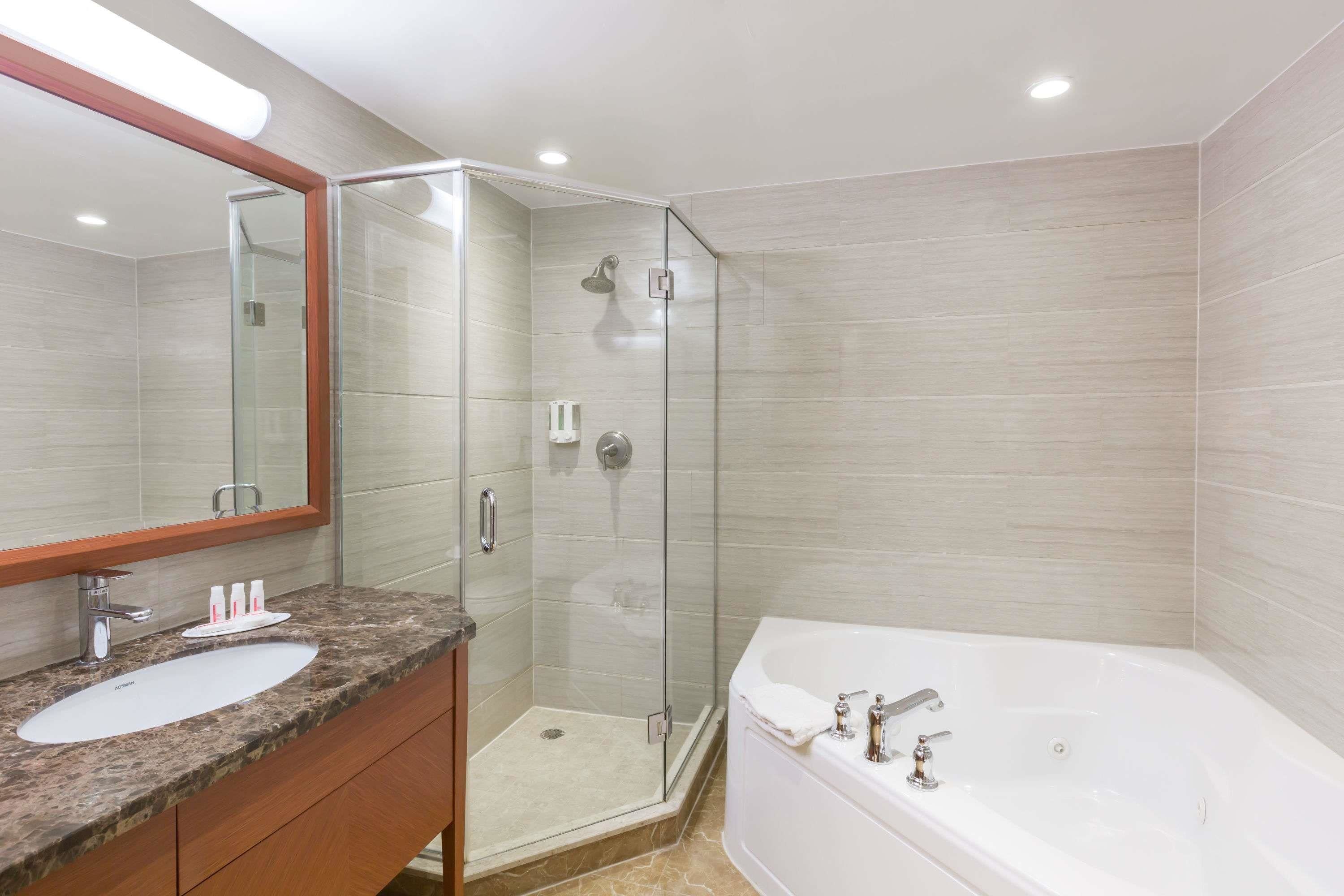 A modern bathroom with a glass-enclosed shower, a white sink, and a large bathtub.