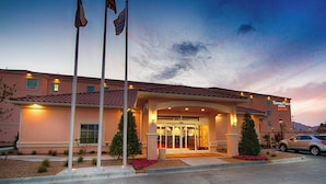 A TownePlace Suites hotel with a prominent entrance, flagpoles, and a well-lit facade. - TownePlace Suites El Paso Airport (El Paso)