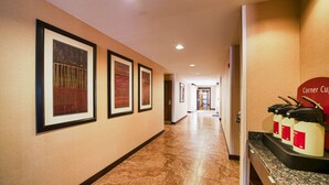 A hotel corridor with framed artwork on the walls, a coffee station, and a door at the end. - TownePlace Suites El Paso Airport (El Paso)