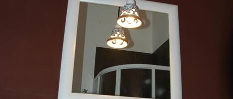 A bathroom with a white sink, a mirror, and a decorative wall piece above the mirror.