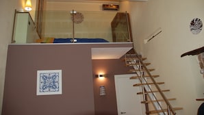 A room with a loft bed, a staircase, and a decorative wall piece. - Locanda Re Ruggero (Monreale)