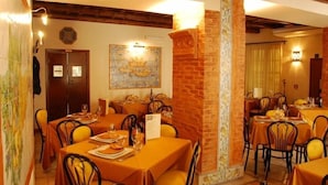 A restaurant with multiple tables, each set with plates, glasses, and cutlery. There are brick walls and wooden beams on the ceiling. - Locanda Re Ruggero (Monreale)