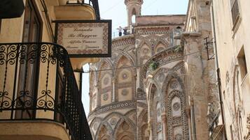 A building with ornate architectural details and a sign indicating "Locanda Re Ruggiero" with "Affitta Camera" and "Rooms" listed.