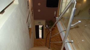 A staircase with wooden steps and metal handrails, leading to an open area with a plant and a door. - Locanda Re Ruggero (Monreale)