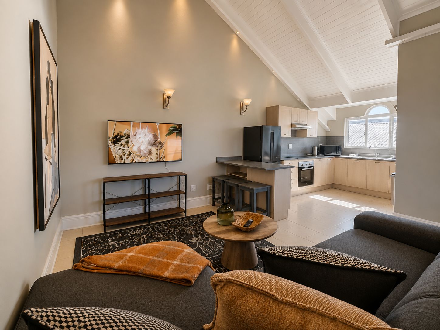A modern living room with a sofa, a coffee table, and a TV mounted on the wall.