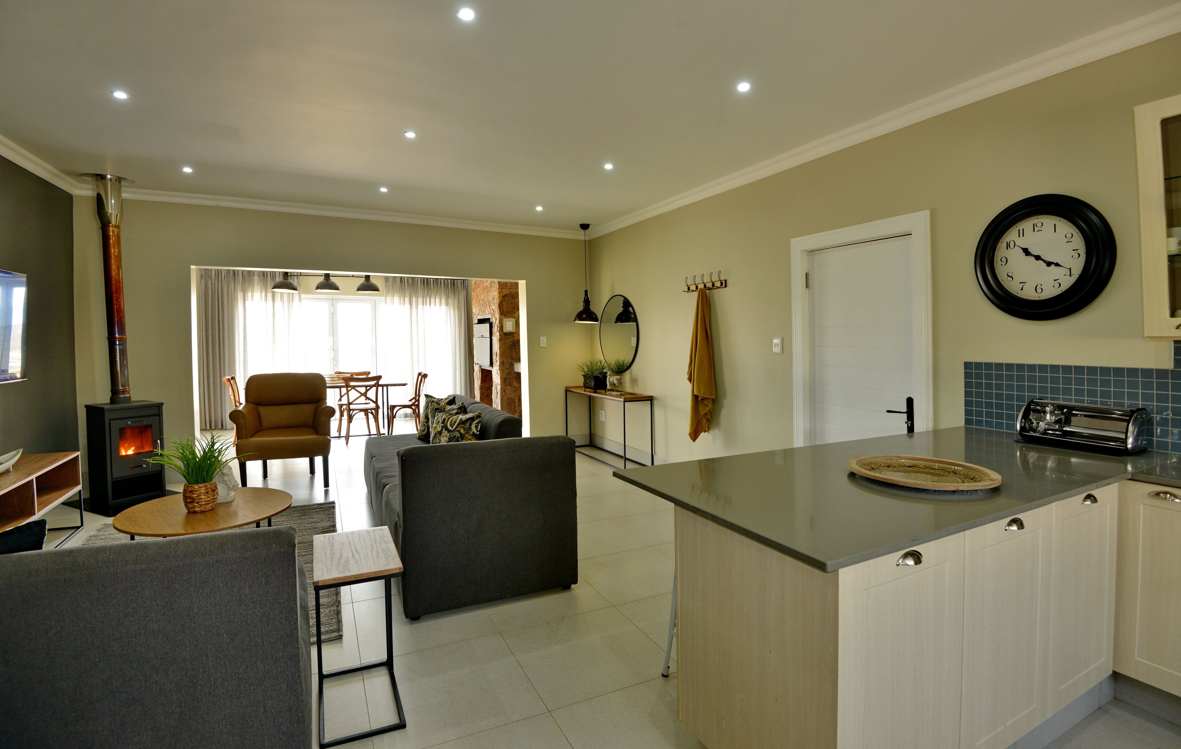 A modern kitchen with a central island, a dining area with a sofa and chairs, and a living room with a fireplace.
