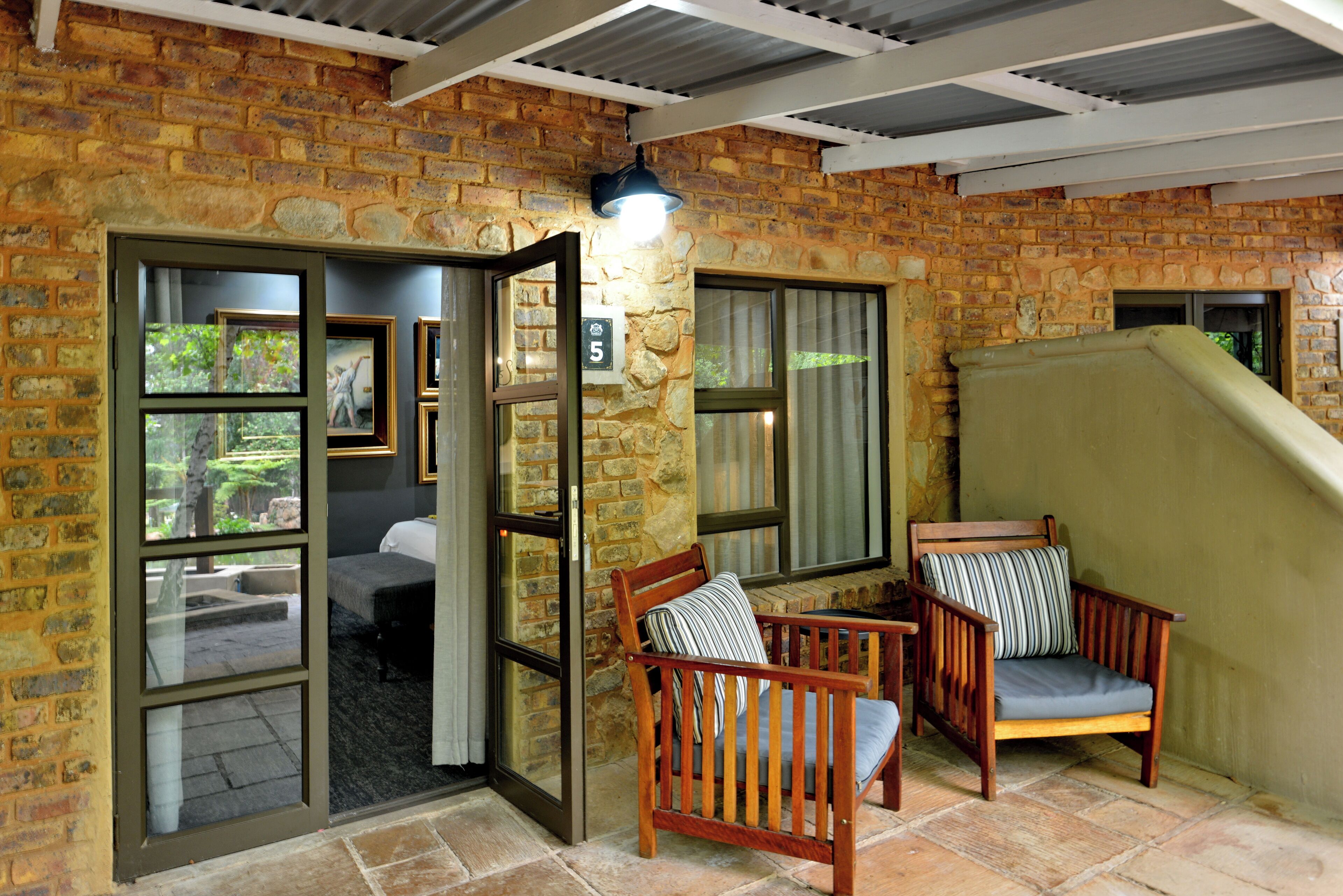 A room with a brick wall, a wooden chair, a bed, and a window.
