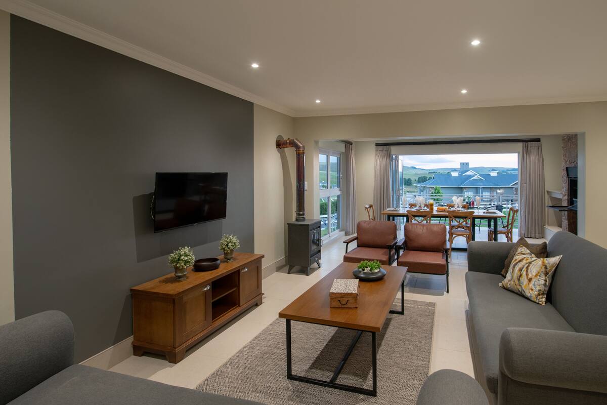 A modern living room with a flat-screen TV, wooden entertainment unit, and a sofa.