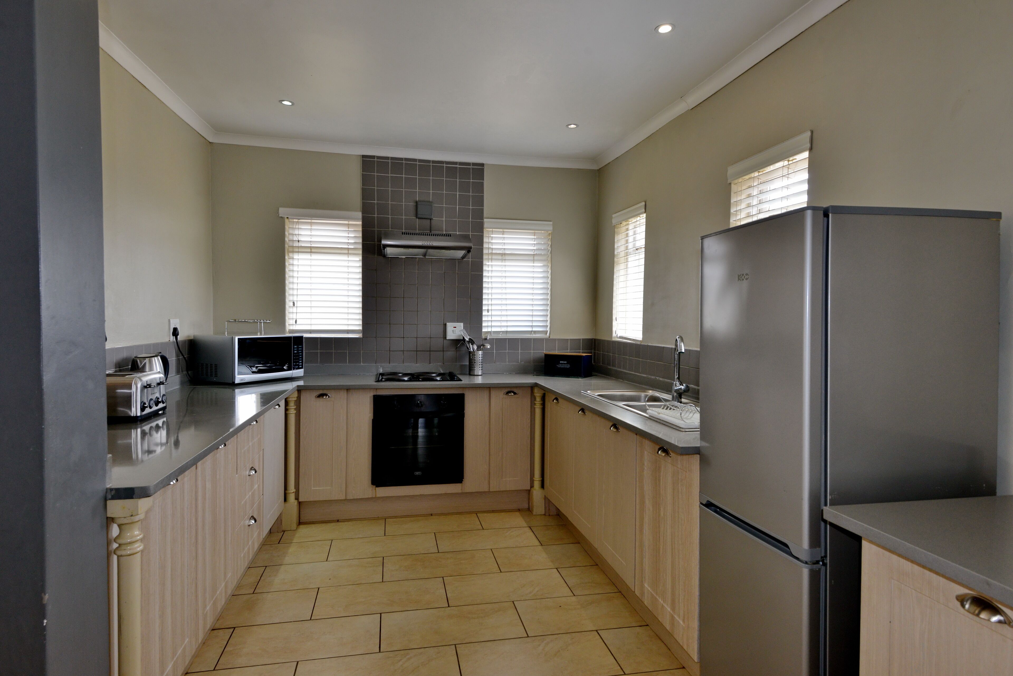 A modern kitchen with a dishwasher, microwave, toaster, and a stainless steel refrigerator.