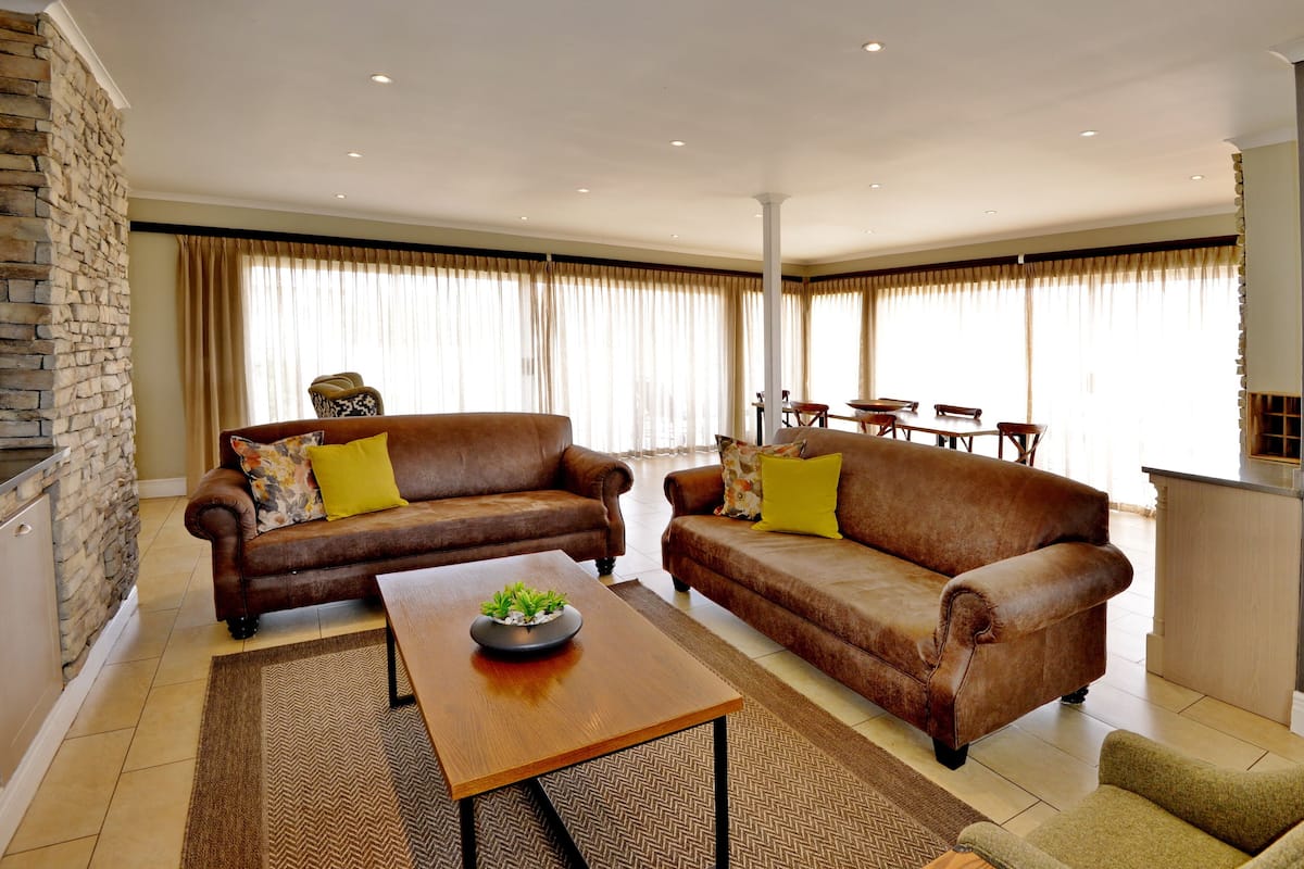 A spacious living room with two brown leather sofas, a wooden coffee table, and a stone accent wall.