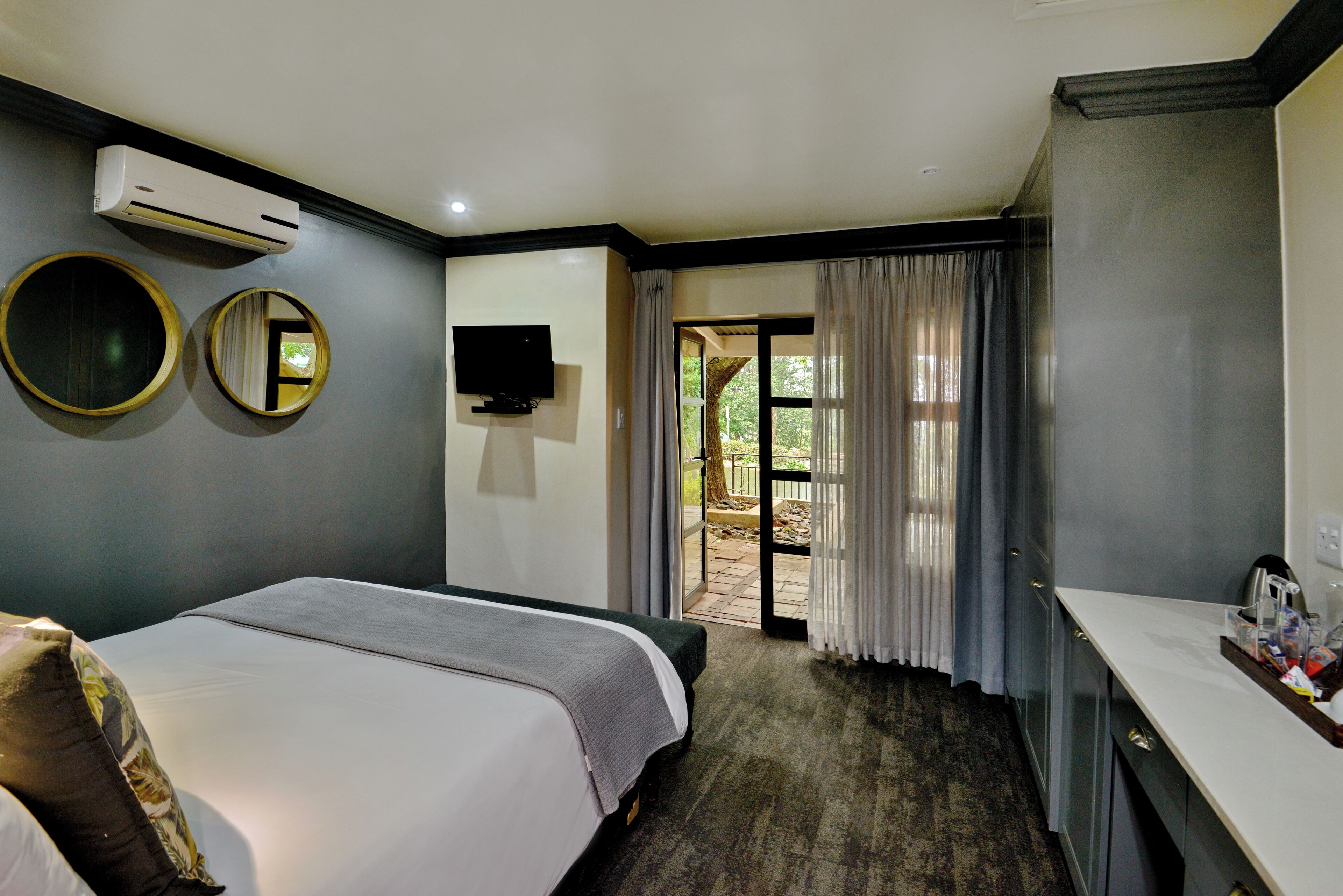 Una habitación de hotel con cama, televisión, escritorio y vistas al exterior.