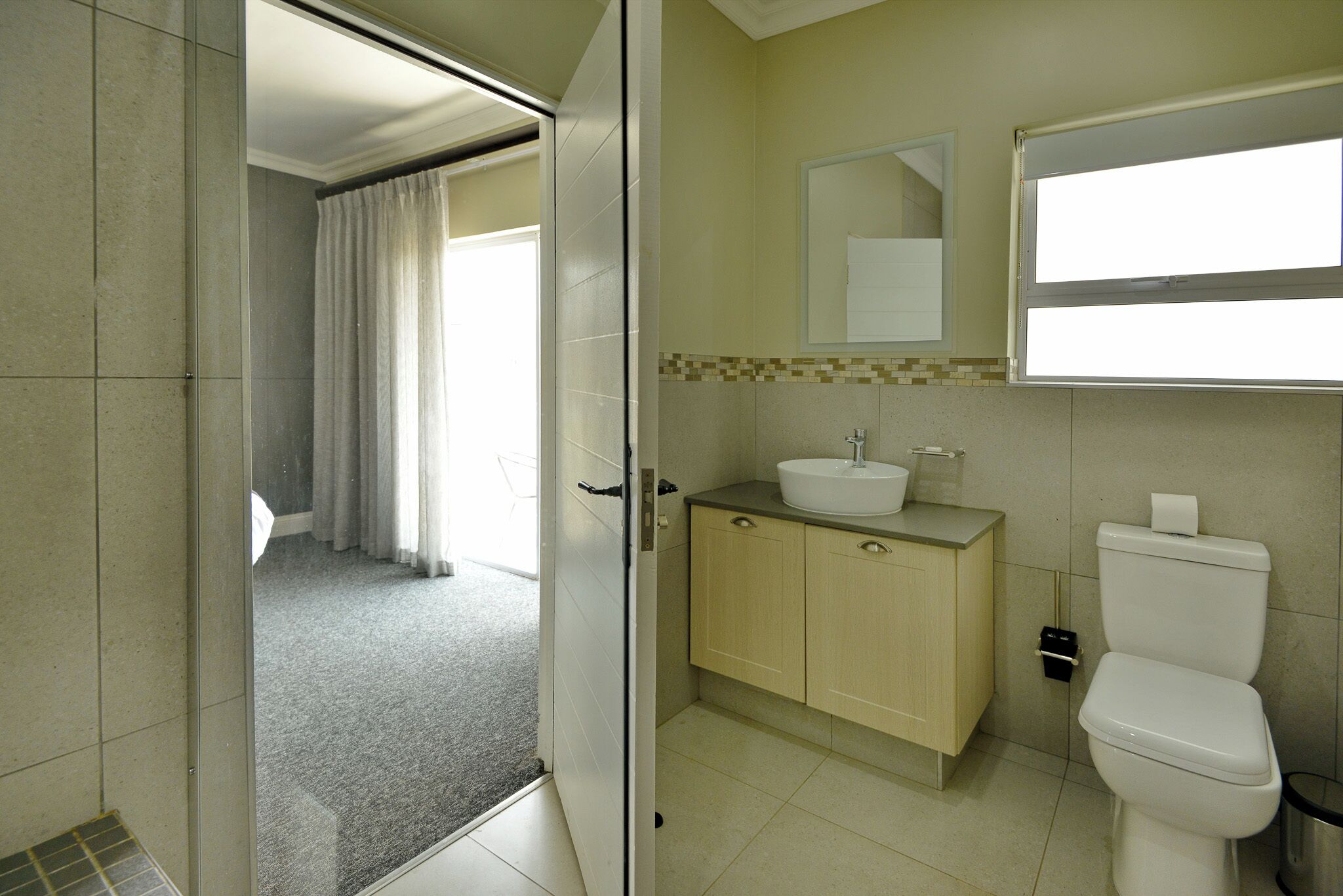 A bathroom with a toilet, sink, and mirror.