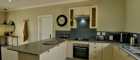A modern kitchen with a central island, built-in oven, microwave, and toaster.